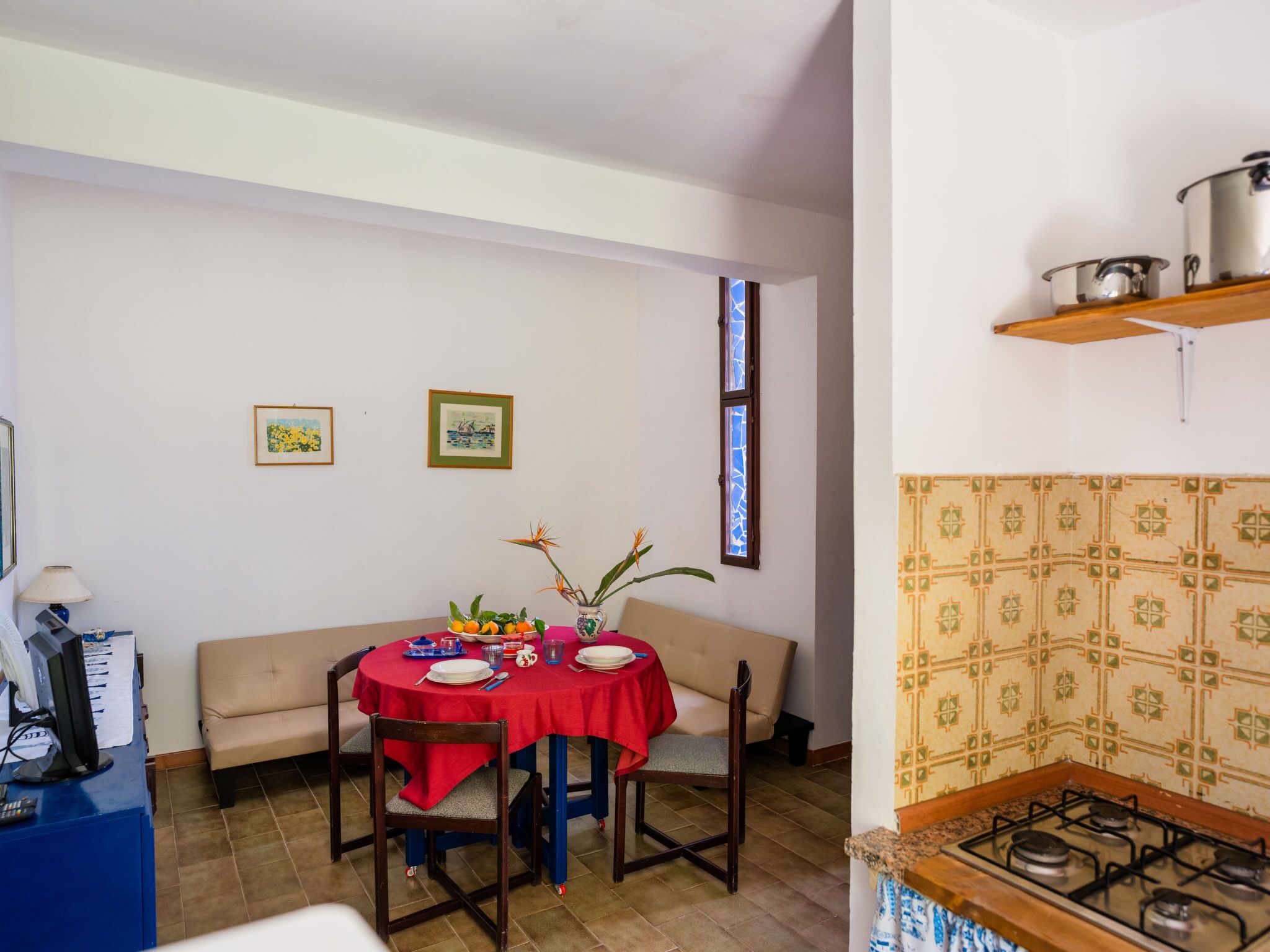 Un comedor con una mesa redonda para cuatro personas, un sofá y una cocina con estufa a gas.