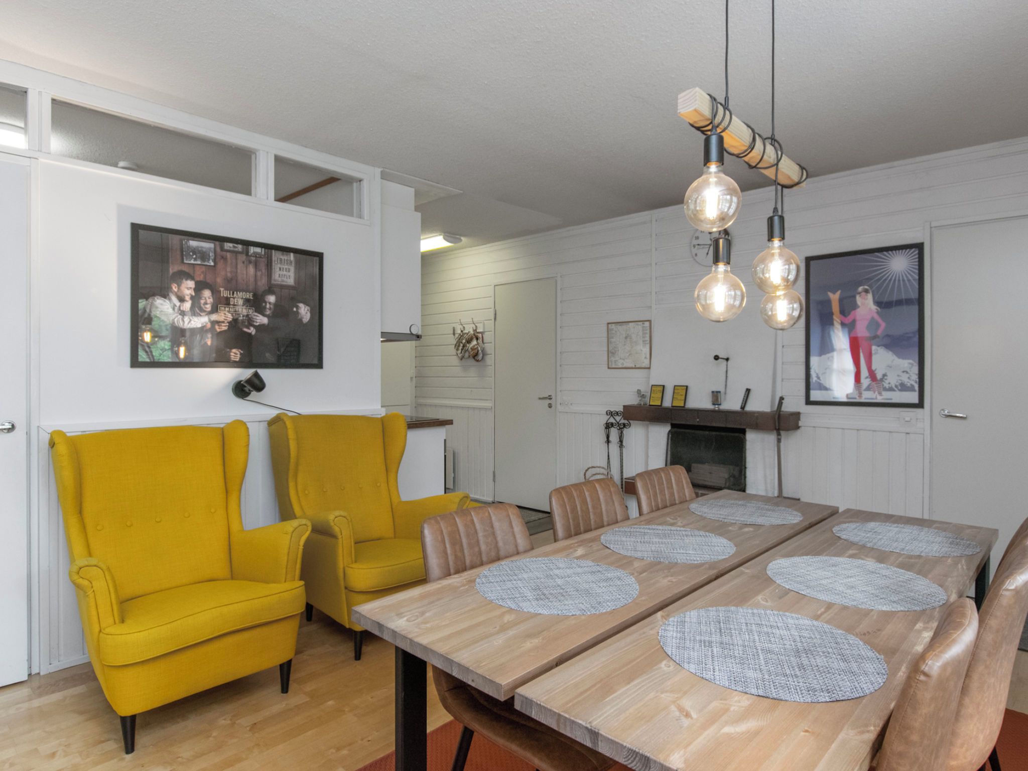 A dining area with a wooden table, yellow chairs, and a hanging light fixture.
