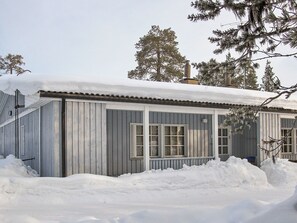 A single-story building with a metal exterior, large windows, and a snow-covered roof.