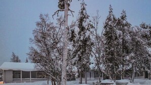 A snow-covered landscape with a house and trees.