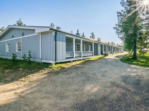 A row of single-story buildings with a porch, a gravel driveway, and trees in the background. - Saariseläntie 8 e 3 by Interhome (Inari)