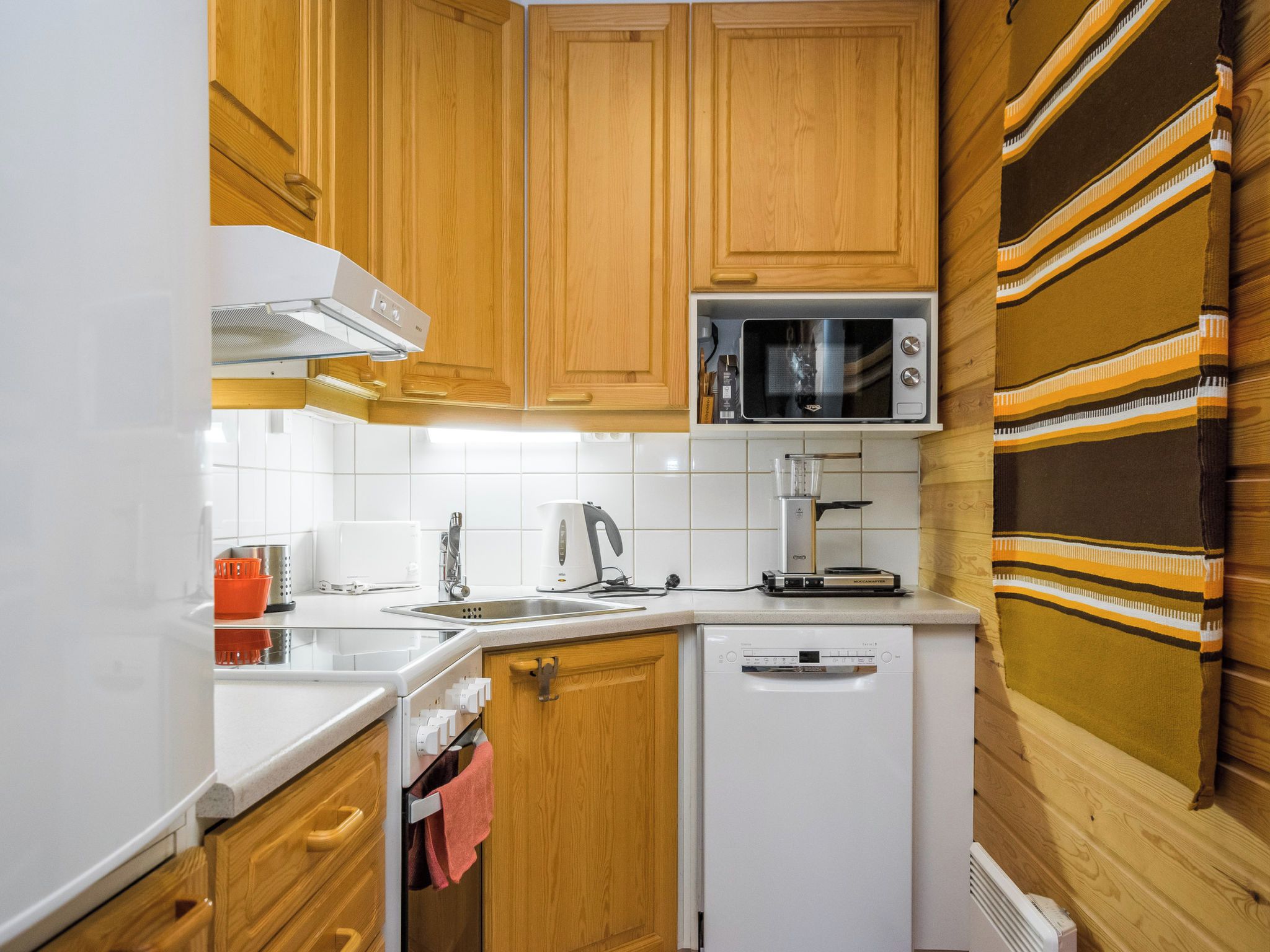 Cocina con armarios de madera, microondas, tostadora y lavavajillas.