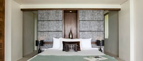 A modern hotel bedroom with a large bed, two bedside tables, and a unique textured wall behind the bed.