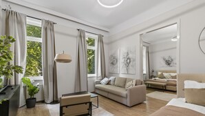 A modern, well-lit living room with a sofa, a dining table, and a large mirror. - Belvedere Apartments (Vienna)