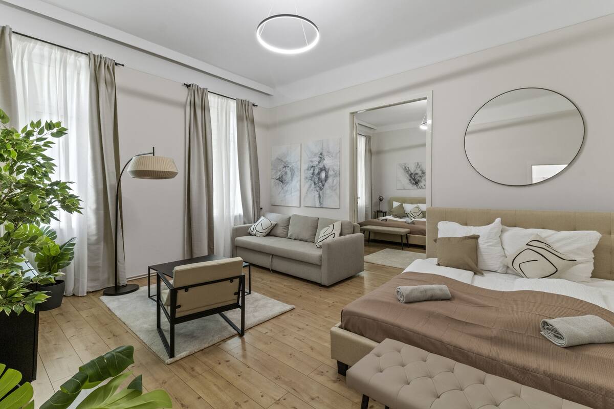 A modern, well-lit bedroom with a large bed, a sofa, and a desk.