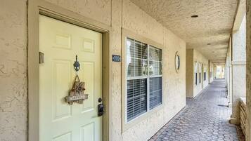A corridor with a light green door, a welcome sign, and a window with blinds.