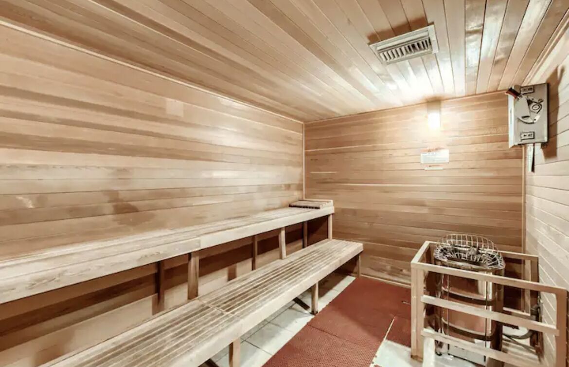 A sauna room with wooden benches and a metal rack for towels.
