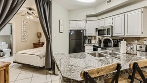 A compact kitchen with white cabinets, a granite countertop, and a built-in microwave. - Puerto Azul - The Island at Lake Travis (Lago Vista)