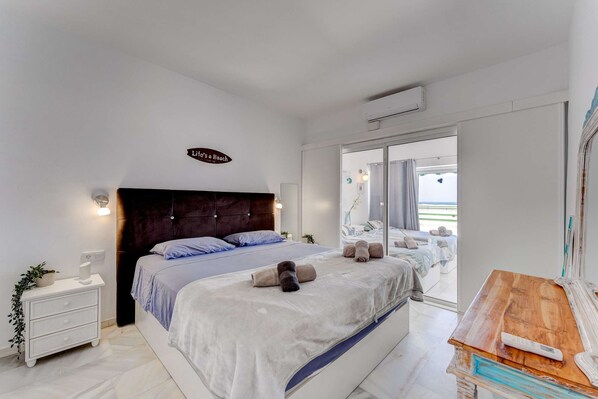 Relax in this serene bedroom with a large bed, bedside table, and stunning beach views.