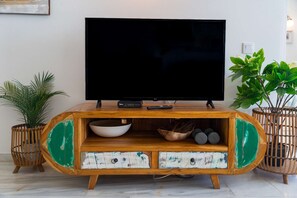 A wooden entertainment center with a flat-screen TV, a remote control, and decorative items.