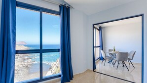 Una habitación con un amplio ventanal que ofrece vistas al mar y a los acantilados.