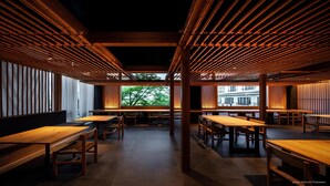 Un intérieur de restaurant moderne avec des plafonds à lambris en bois, de longues tables et des chaises.