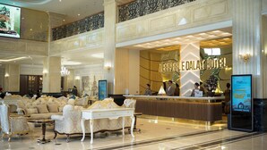 A spacious lobby with a reception desk, seating area, and a large chandelier.