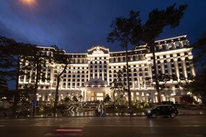 Un hotel grande de varios pisos con una entrada imponente y una fuente al frente.