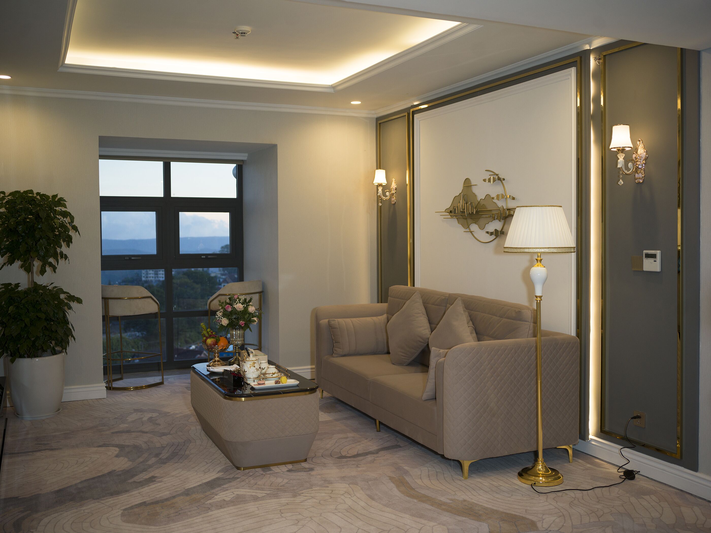 A living room with a sofa, a coffee table, and a floor lamp. There is a window with a view of the outdoors.