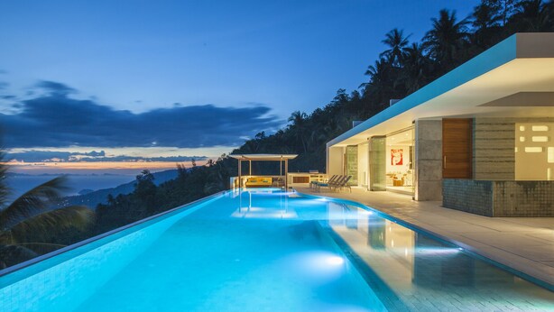 Un área de piscina moderna con una vista despejada de las montañas al fondo.