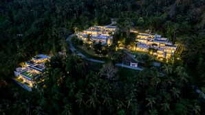 Un resort lujoso con varias construcciones, una piscina y exuberantes jardines tropicales.