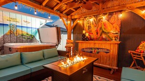 Un espace extérieur accueillant avec un foyer, un jacuzzi et une fresque murale.