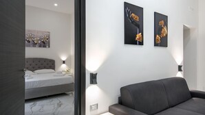 Une chambre moderne avec un lit, un canapé et deux œuvres d’art accrochées au mur.