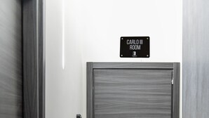 Une porte fermée, avec une pancarte au-dessus indiquant : « SALLE CARLO III ».