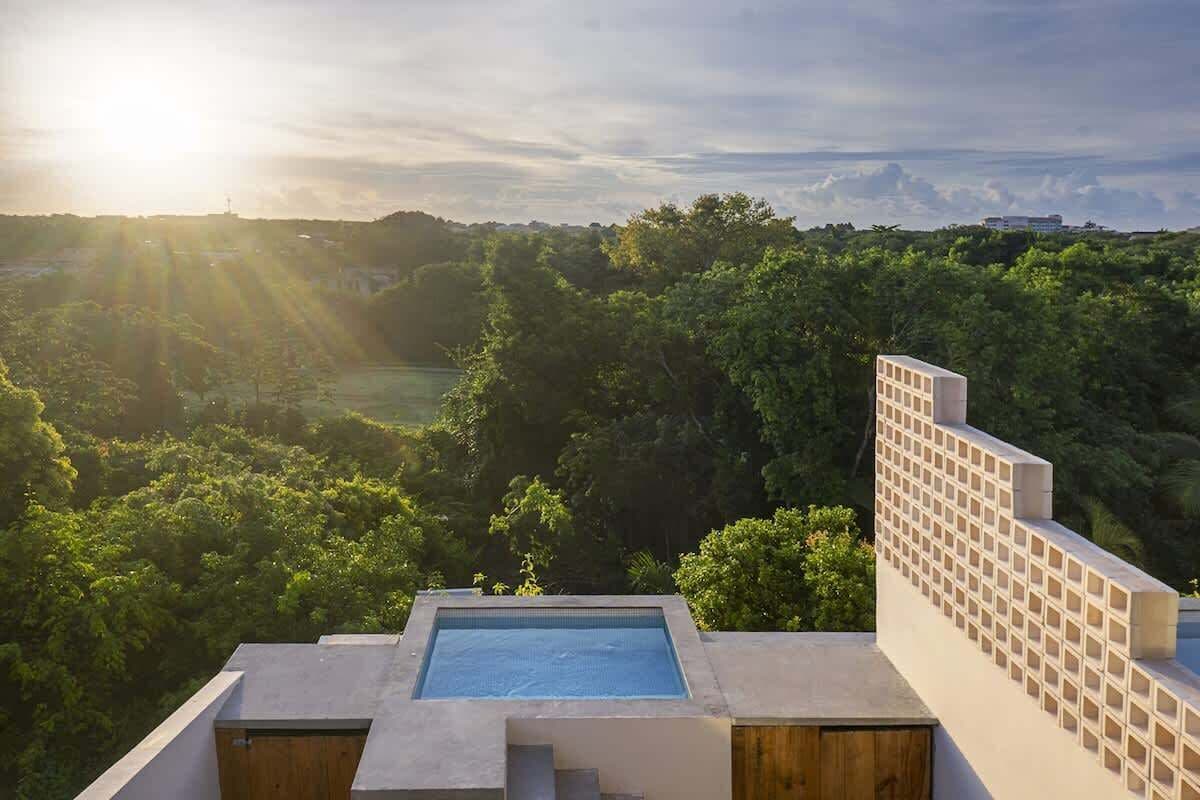 A rooftop pool with a view of a forested landscape.