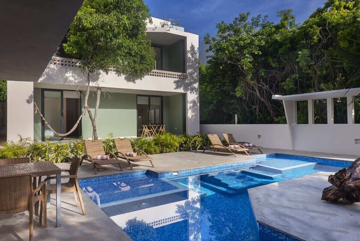 Ein modernes Haus mit Swimmingpool, Gartenmöbeln und  üppiger Bepflanzung.