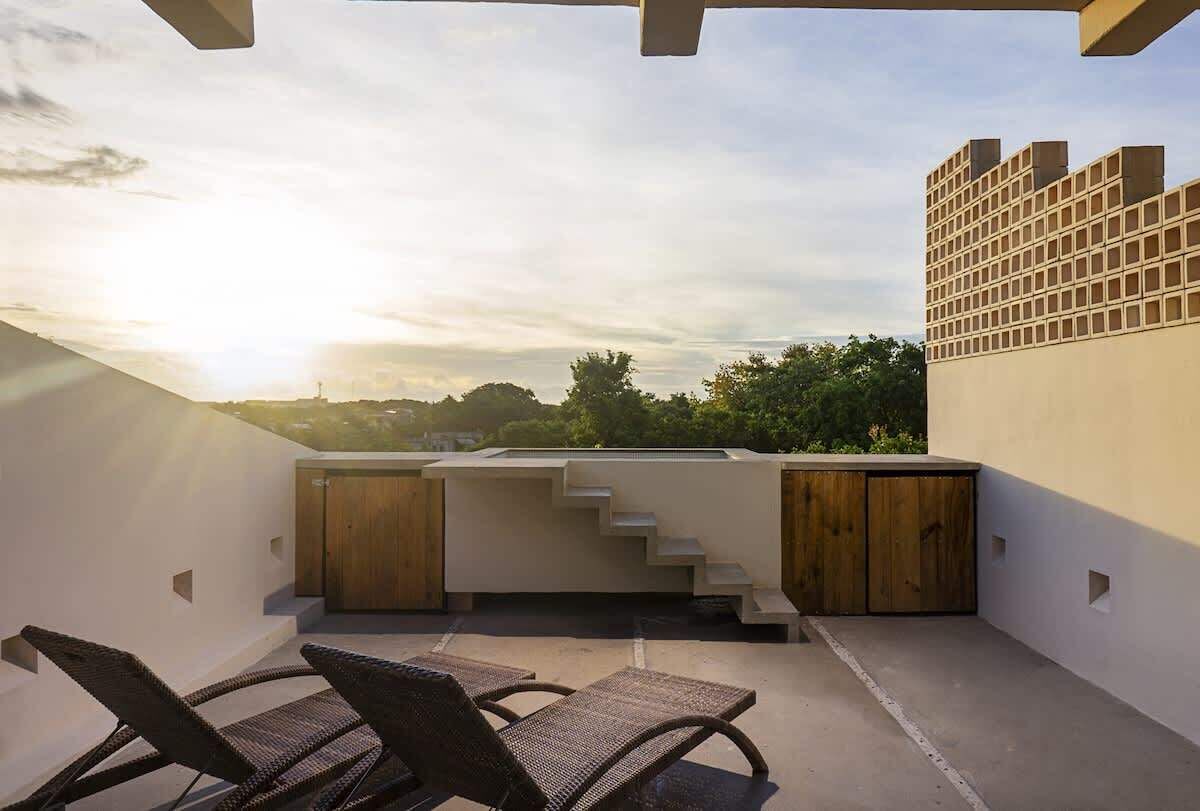 Une terrasse sur le toit, dotée d’un espace salon, d’un meuble en bois et d’un escalier menant à un niveau supérieur.