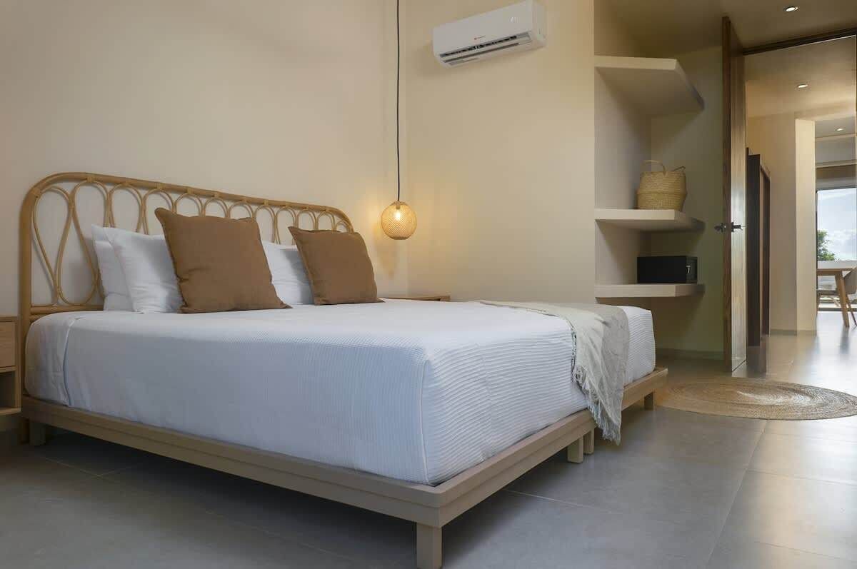 A bed with a wooden frame, white bedding, and a hanging light fixture.