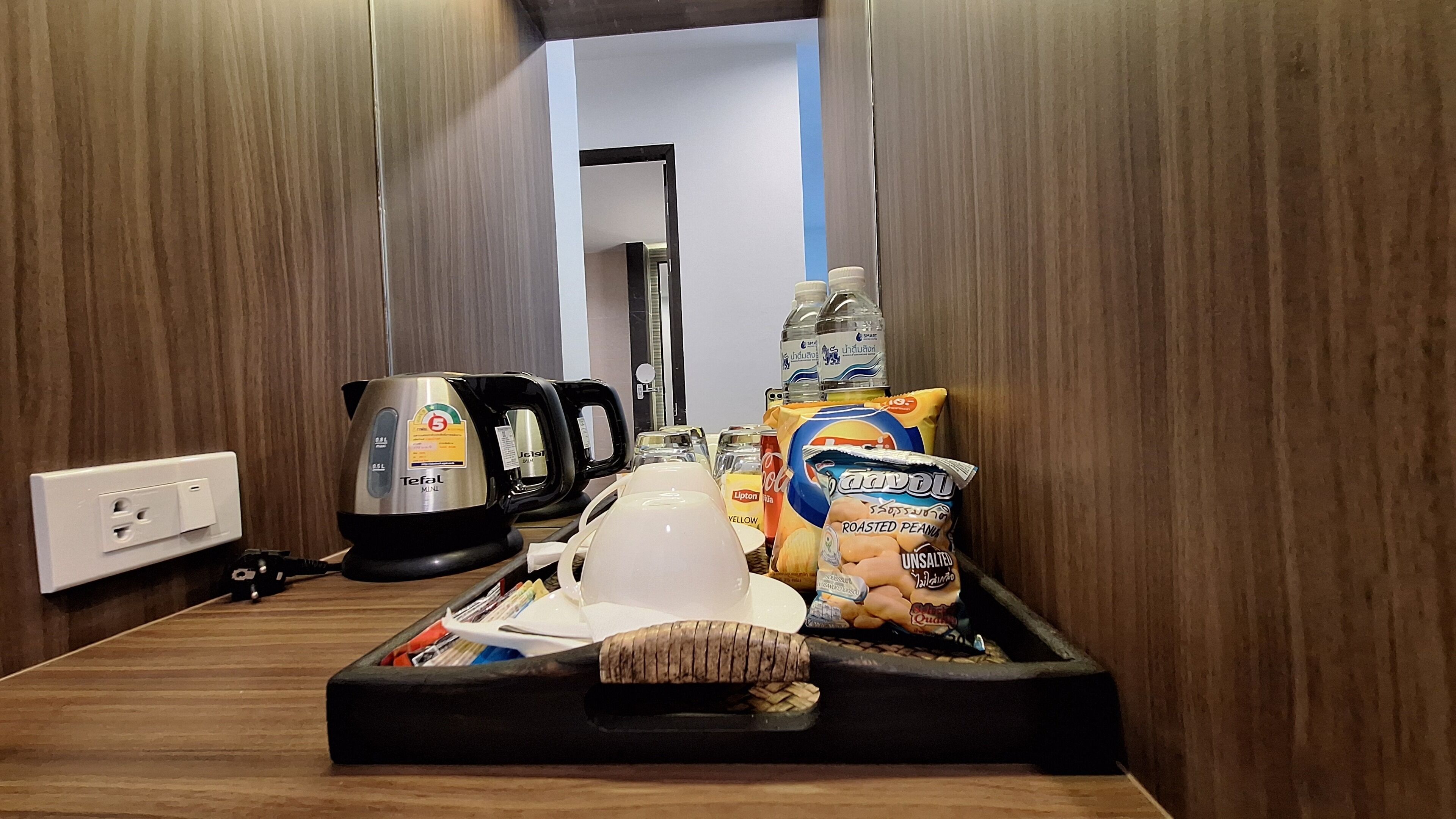 A kitchenette with a coffee maker, kettle, toaster, and food items like chips and a bag of roasted peanuts.