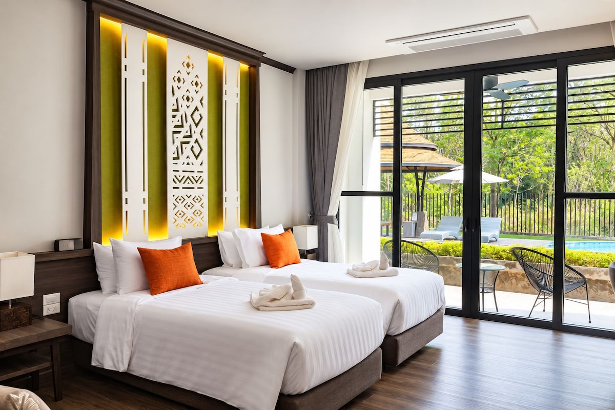 A hotel room with two beds, a large window, and a view of the outdoor pool area.