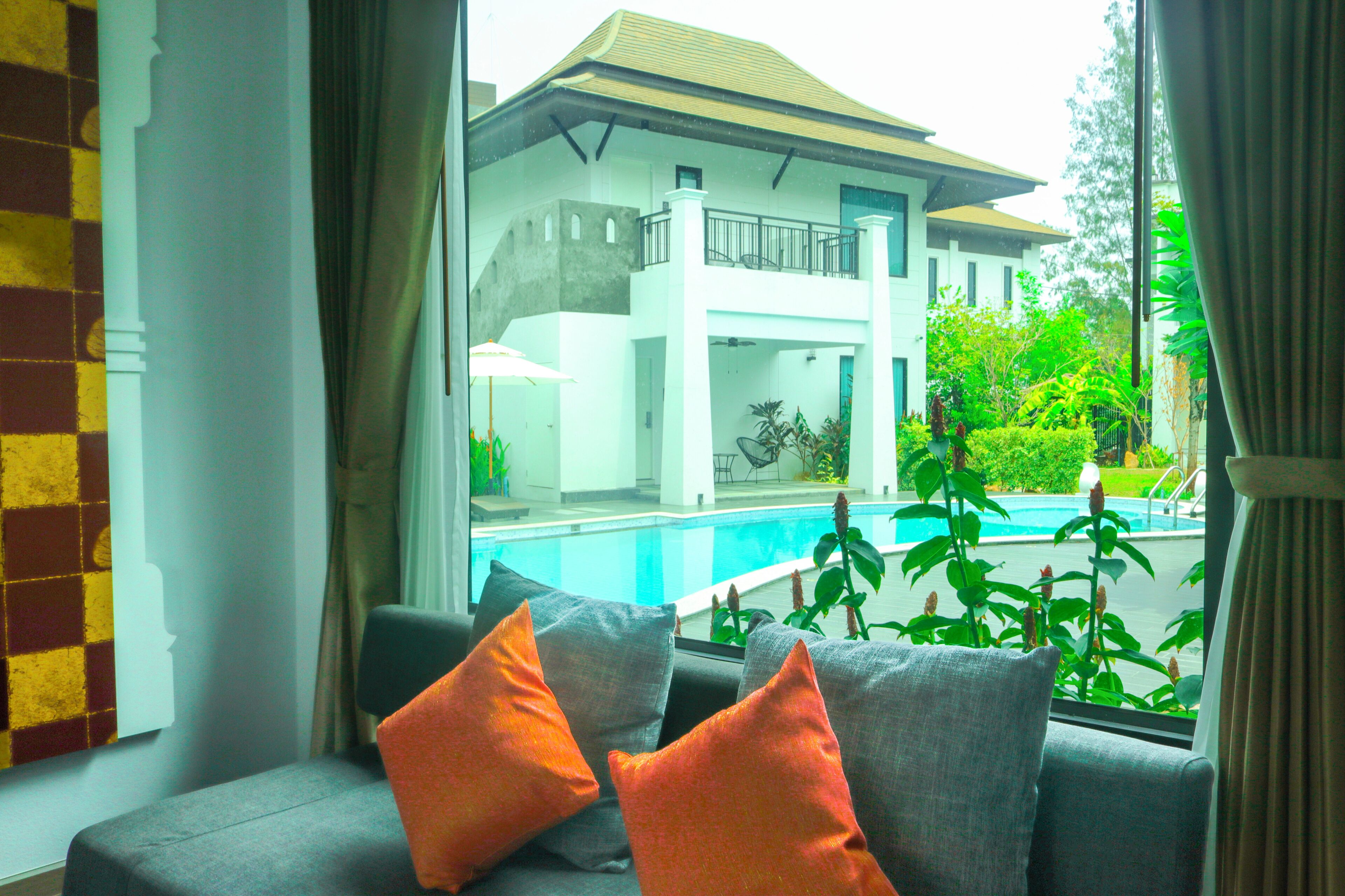 Vista desde una ventana con piscina, balcón y un edificio de fachada blanca.
