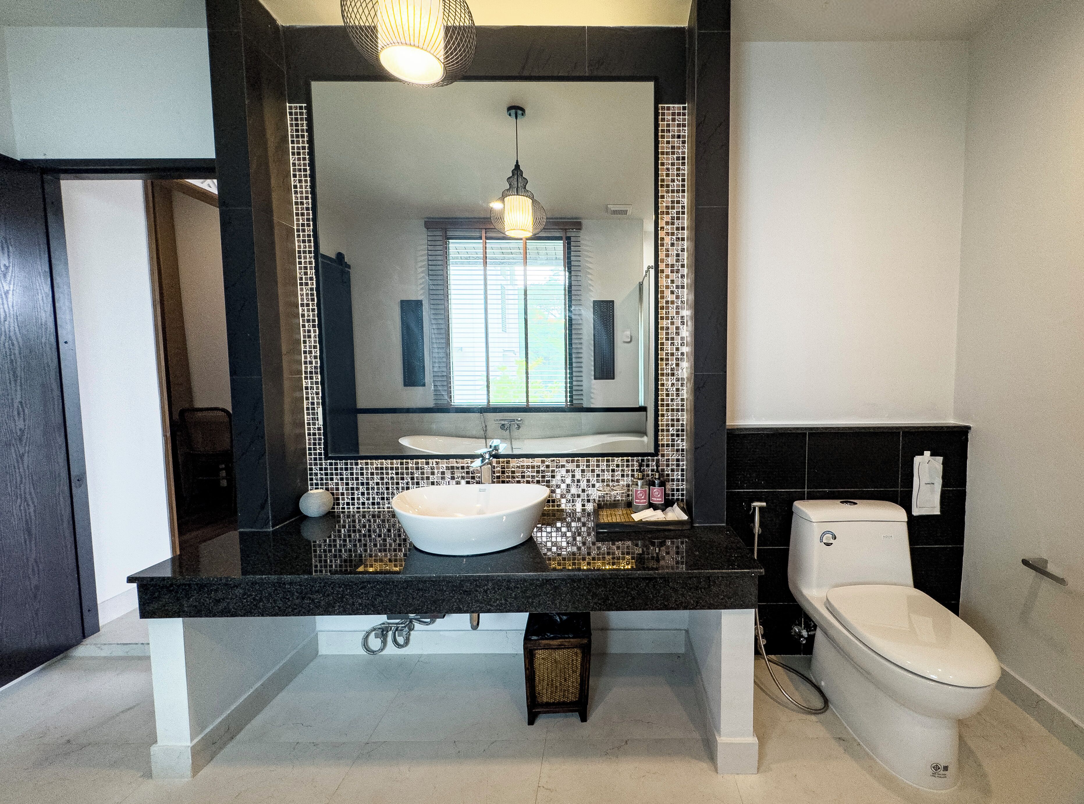 Un baño moderno con un espejo grande, un lavabo y un inodoro.