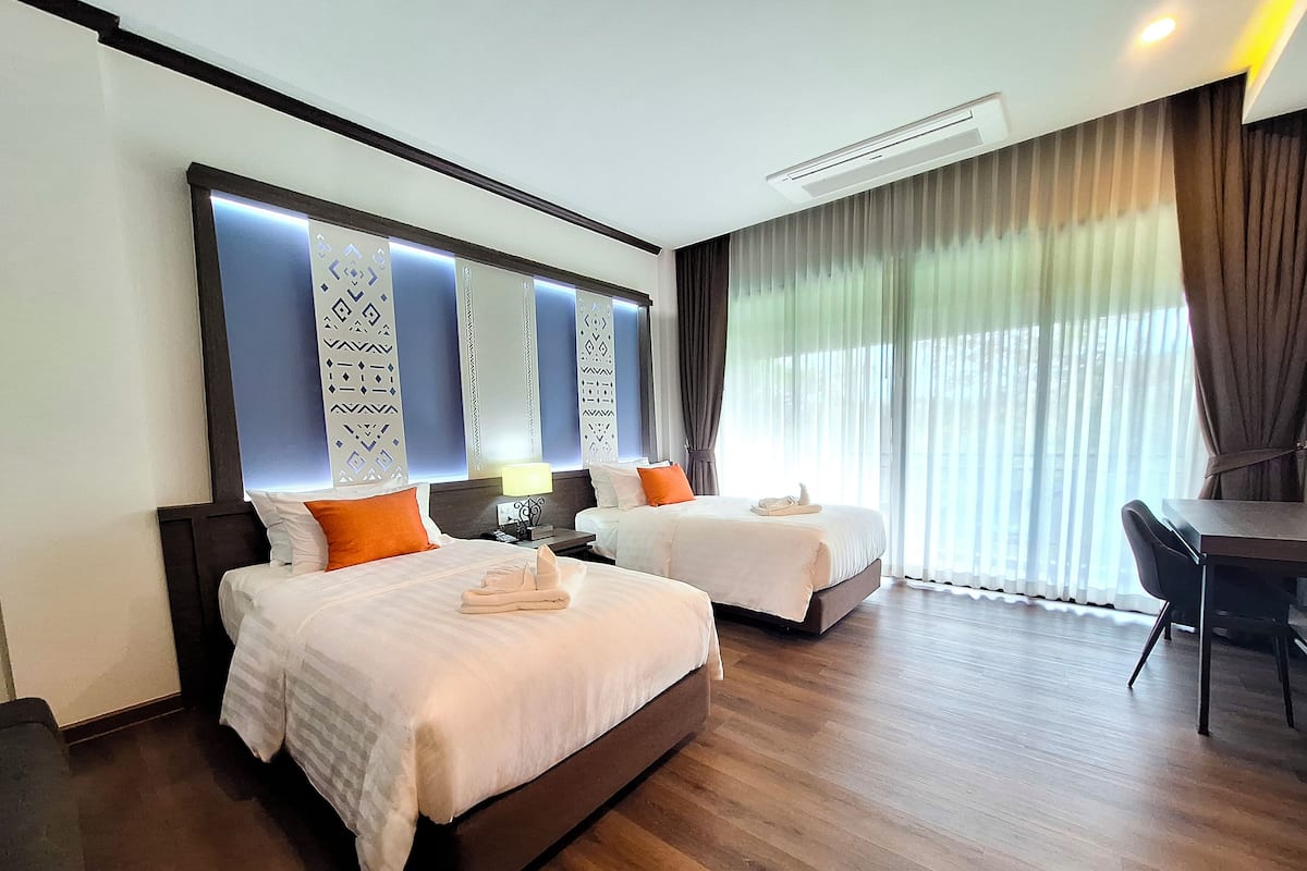 Une chambre d’hôtel avec deux lits, un bureau et une chaise.