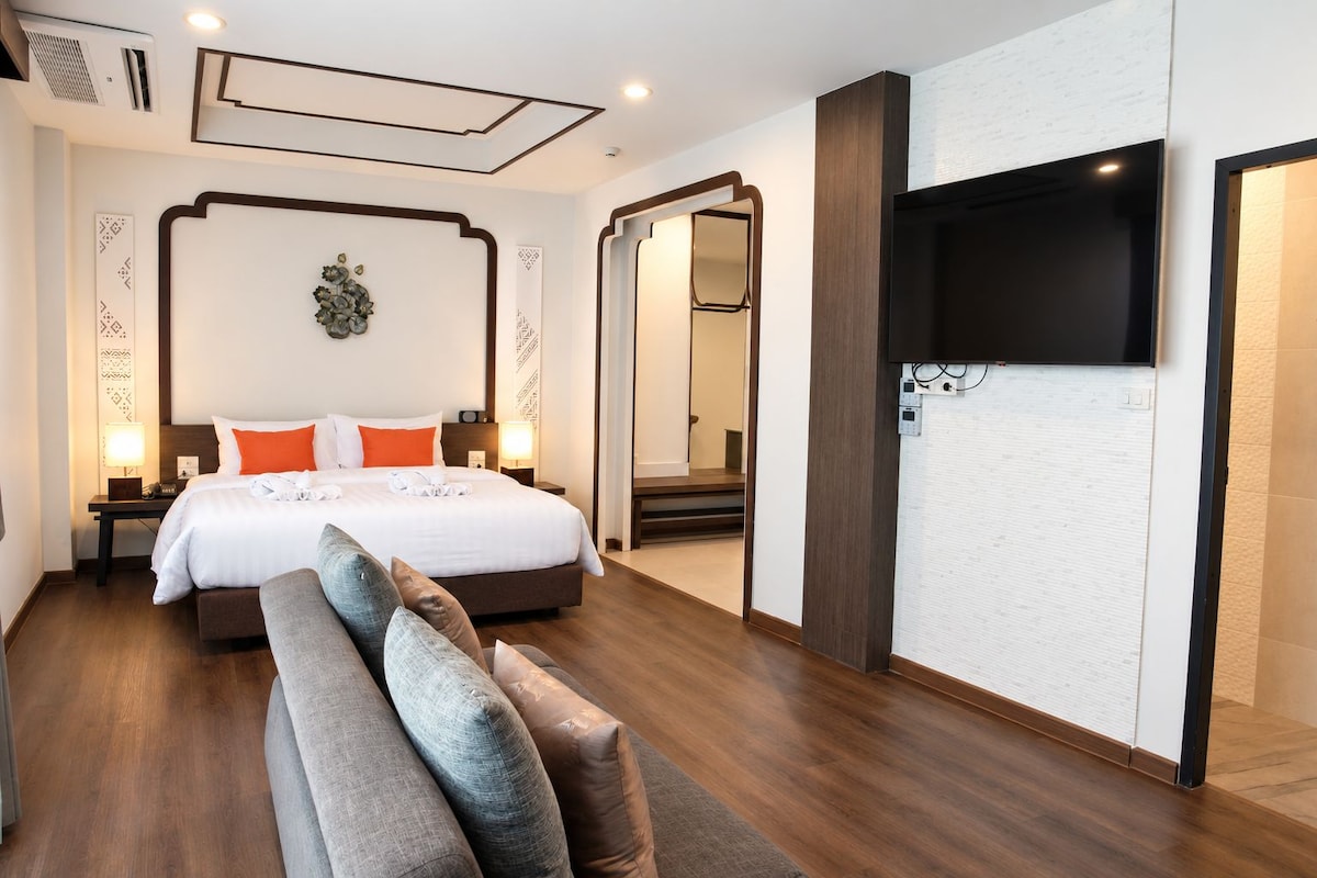 A hotel room with a bed, bedside tables, a TV, and a mirror.