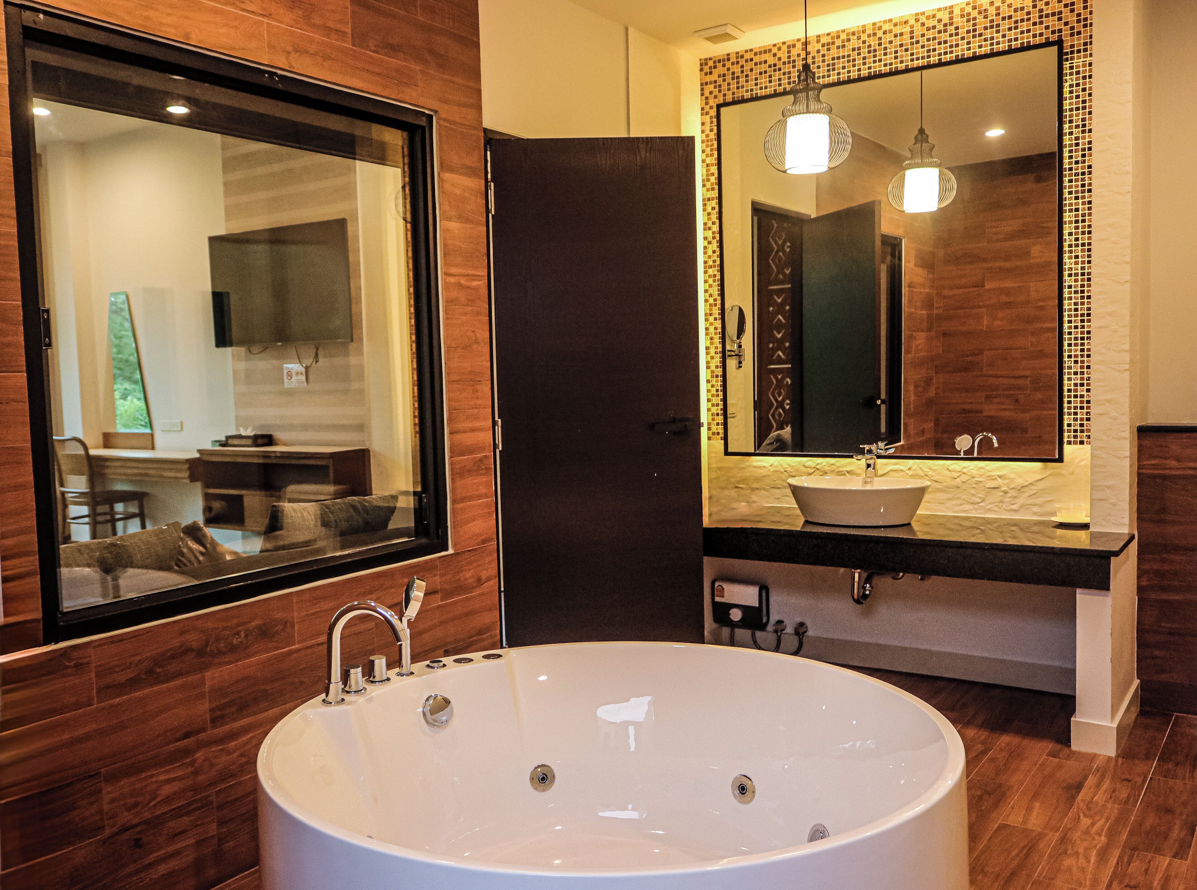 A modern bathroom with a large oval bathtub, a mirror with a mosaic border, and wooden paneling.