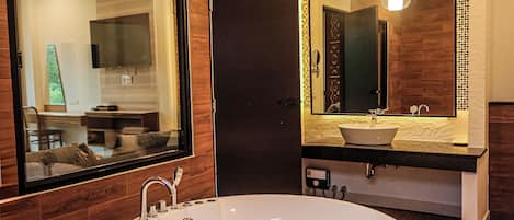 A modern bathroom with a large oval bathtub, a mirror with a mosaic border, and wooden paneling.