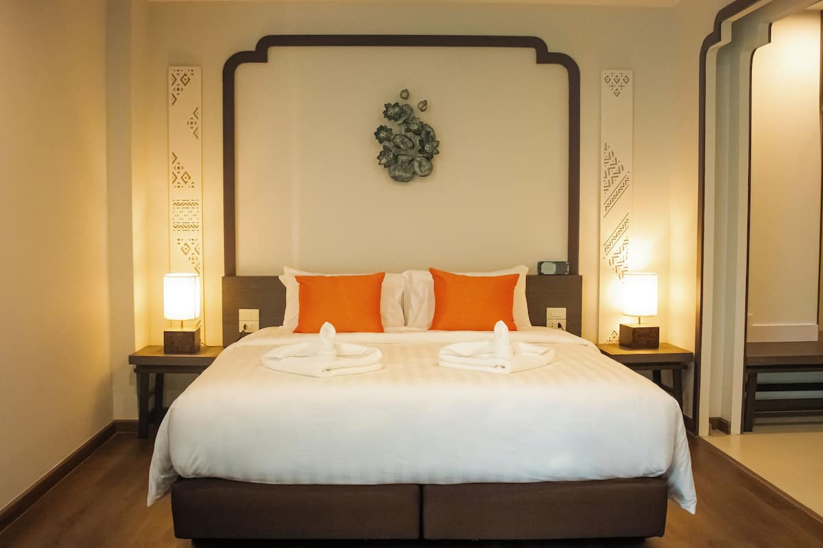 Une chambre d’hôtel avec un grand lit, deux tables de chevet avec des lampes et un élément décoratif mural au-dessus du lit.