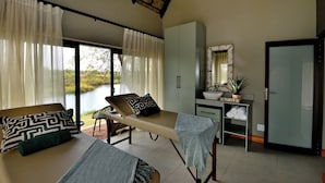 Ein Zimmer mit Massagetisch, Schreibtisch mit Waschbecken und Blick auf einen See.