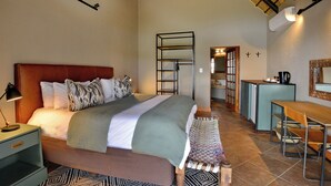Ein Schlafzimmer mit einem Bett, einem Nachttisch und einem Schreibtischbereich mit Stühlen.