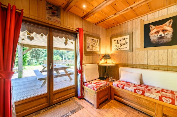 A wooden cabin interior with a bench, a table, and a framed fox picture.