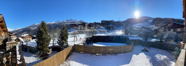 A snow-covered ski resort with wooden buildings, a wooden fence, and a clear view of the mountains in the background. - Apartment "Les Dolomites" with Mountain View, Private Terrace and Wi-Fi (La Plagne-Tarentaise)