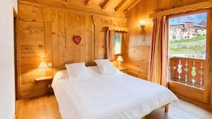 A wooden room with a bed, two bedside lamps, a heart-shaped decoration, and a window with curtains. - Apartment "Les Dolomites" with Mountain View, Private Terrace and Wi-Fi (La Plagne-Tarentaise)