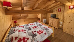 Een houten kamer met een bed, een televisie en een kleine kitchenette.