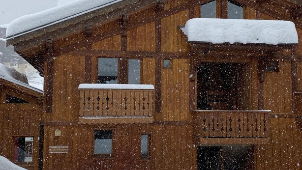 Een houten gebouw met balkon en sneeuw.