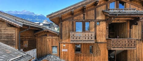 A wooden chalet with balconies, a mountain view, and a traditional alpine architectural style.