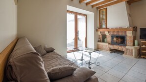 Una sala de estar con sofá, chimenea y vistas a través de un ventanal.