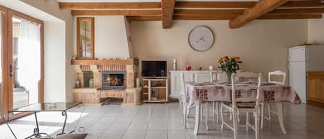 Una sala de estar con chimenea, una mesa de comedor y un televisor.