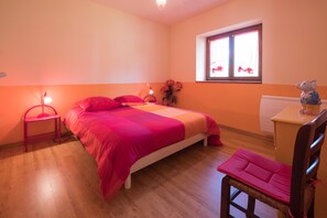 Quarto com cama, cadeira, escrivaninha, luminária e janela.