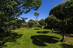 A well-maintained garden with various trees and a clear blue sky. - Villa "Golfvilla Riviera" with Sea View, Private Pool & Wi-Fi (Grimaud)