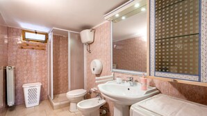 A bathroom with a toilet, bidet, sink, and shower.